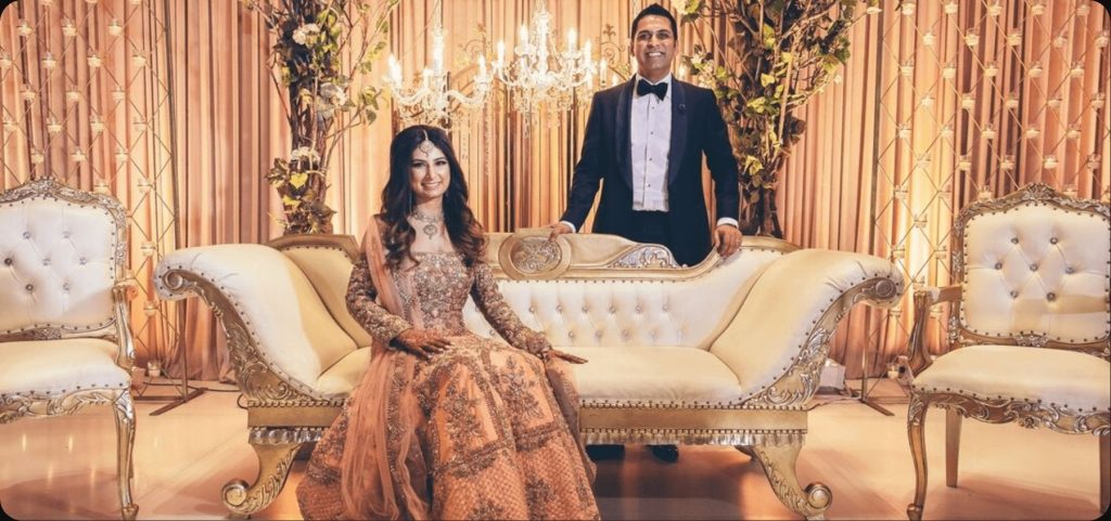 Couple in coordinated Aayra wedding outfits, a pastel lehenga and a classic tuxedo