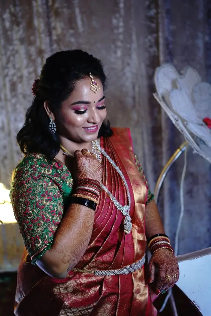 Bride in a red silk saree with a green blouse and gold jewellery