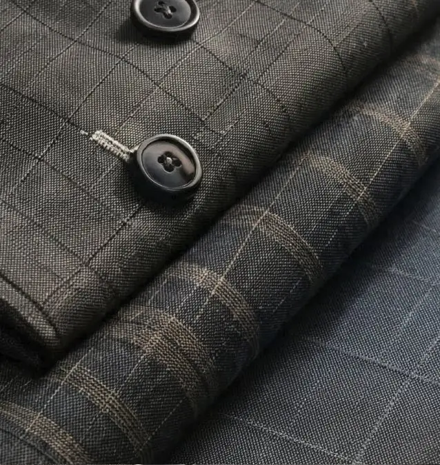 Folded grey and blue check suiting fabric with dark buttons